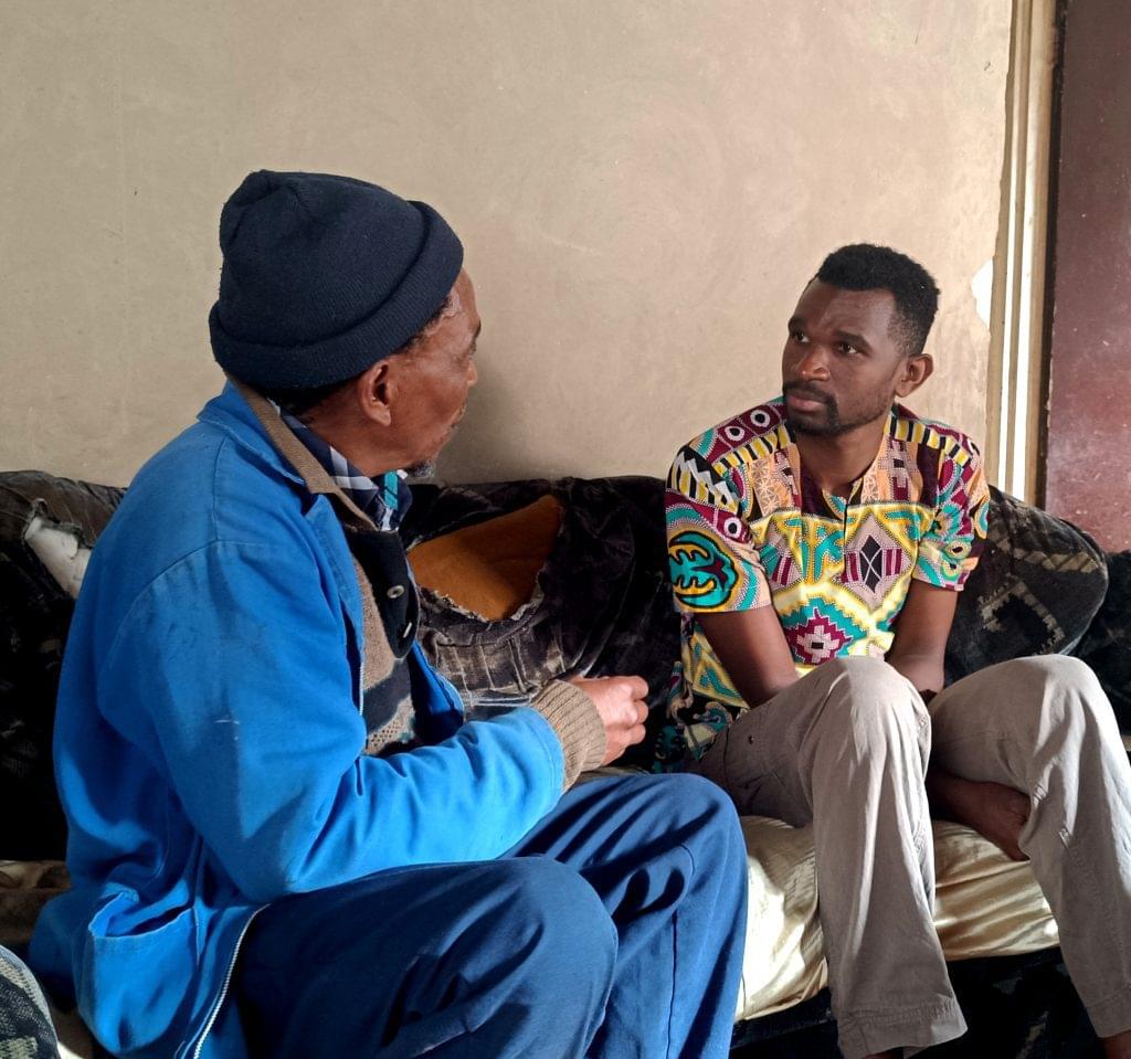 Tatenda is sitting listening to a community member speak